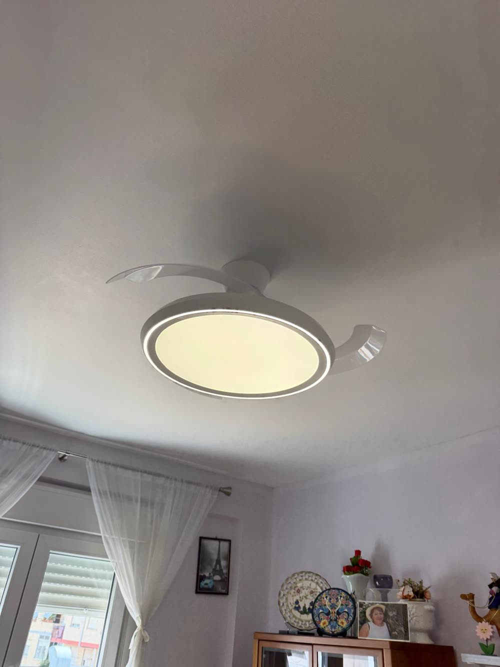 Ventilador de techo con luz LED y aspas retráctiles instalado en un dormitorio